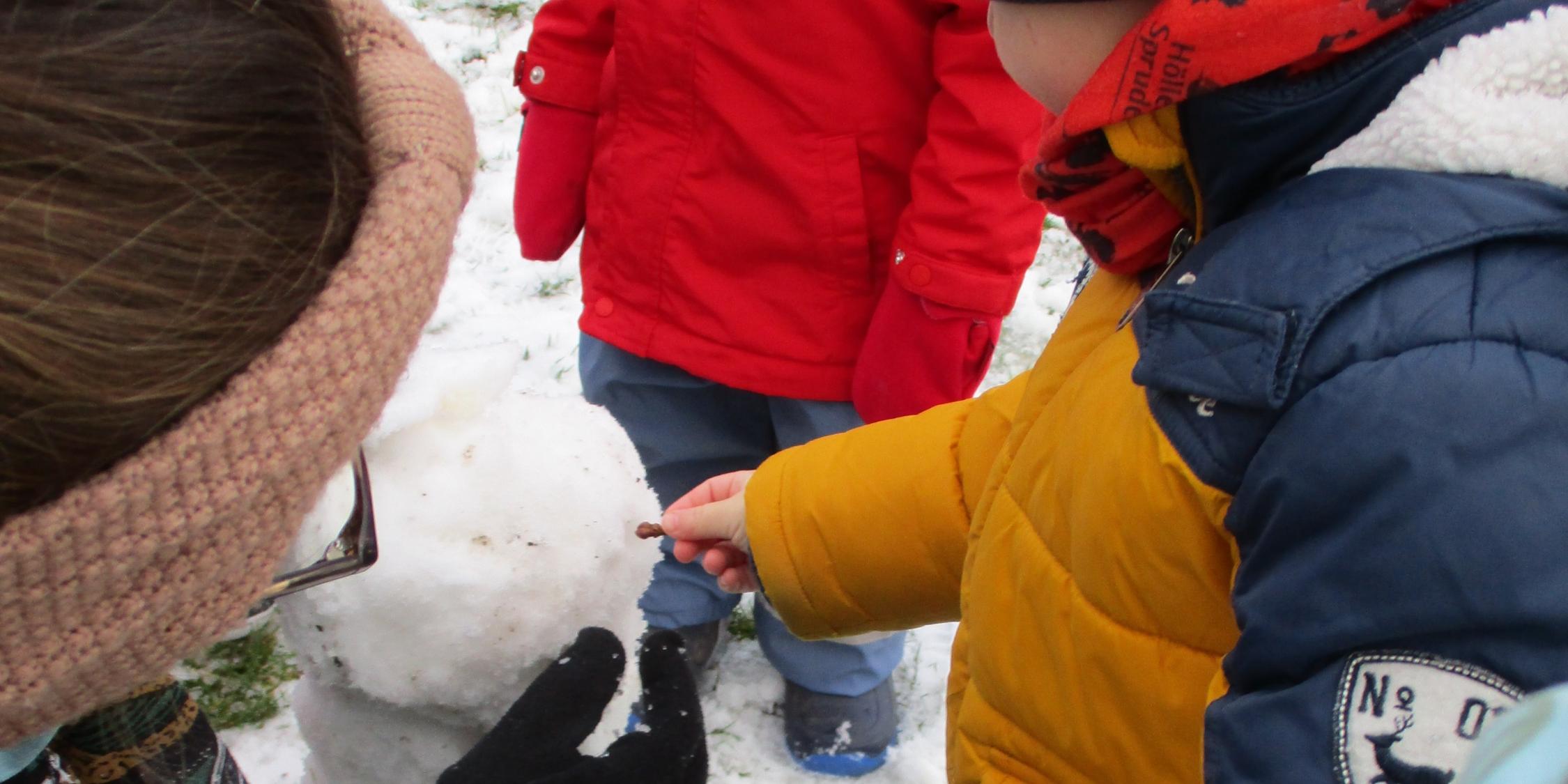 Krippenkinder bauen gemeinsam einen Schneemann