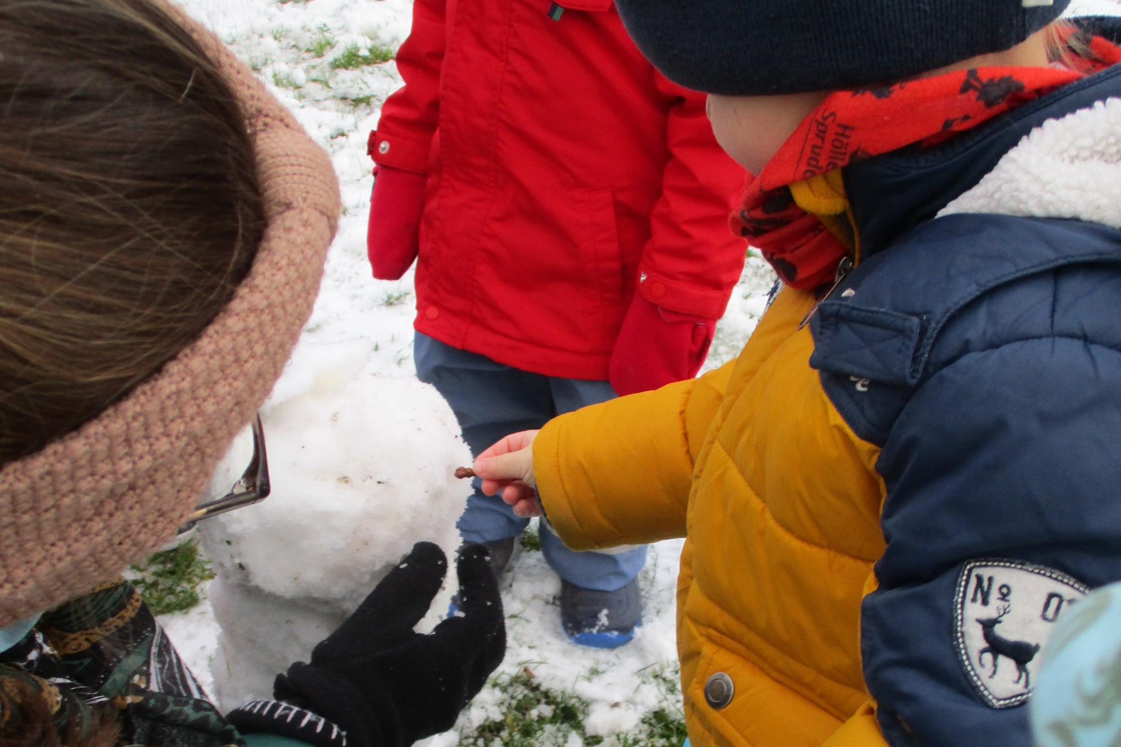 Krippenkinder bauen gemeinsam einen Schneemann